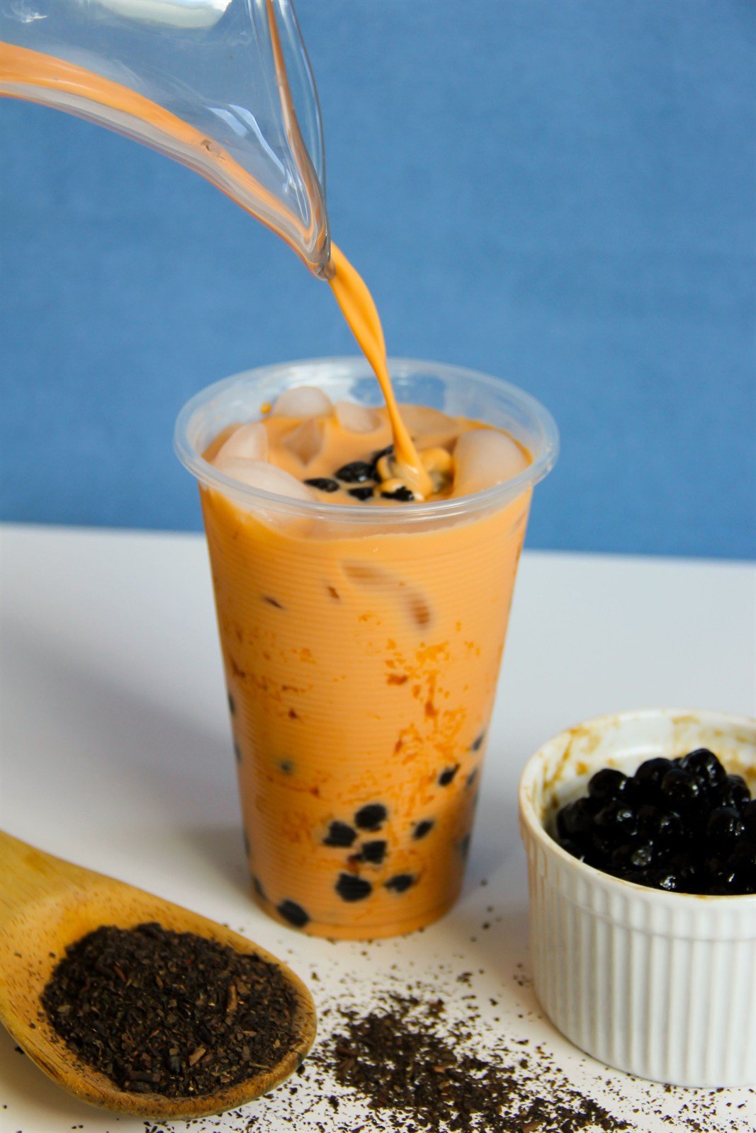 Milk tea with boba being poured into a cup